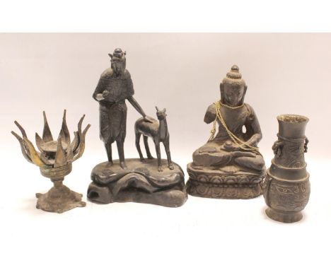 Oriental cast metal figure of a deity standing with deer on naturalistic rocky plinth base, a cast metal figure of Buddha sea