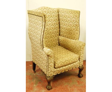 Chippendale-style wing-back armchair upholstered in studded floral fabric, on carved mahogany ball and claw feet, 119cm high.