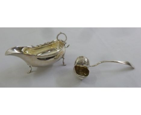 A silver sauce boat, oval cut edge on three scroll feet and an unusual conch ladle