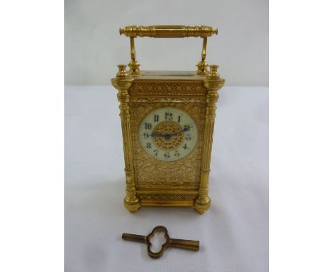A gilded metal carriage clock decorated with filigree sides, enamel dial with Arabic numerals, to include key
