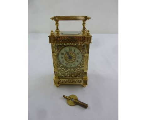 A French brass carriage clock with enamel dial and Arabic numerals, decorative filigree panels and carrying handle