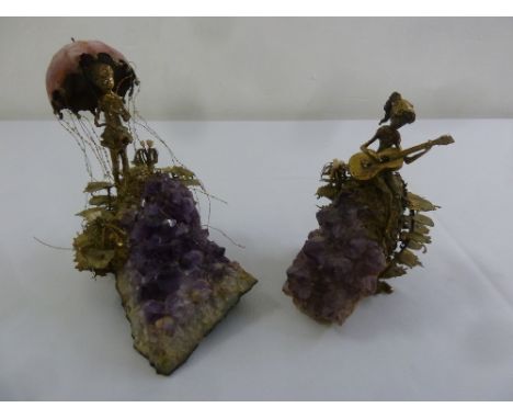A pair of amethyst sculptures with applied metal work enamel and porcelain of figures in a fairytale setting