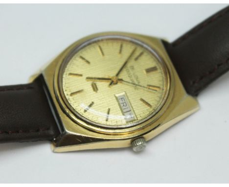 A vintage gold plated Bulova Accuquartz day date wristwatch with gold tone dial, hands and hour batons with black inset, stai