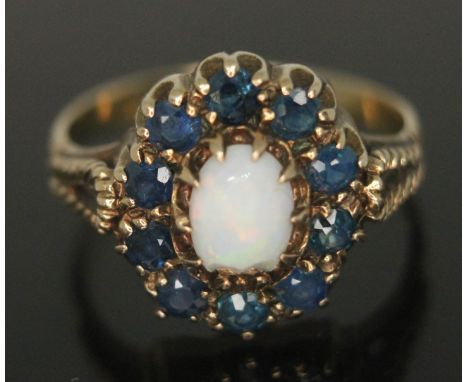 A precious opal and sapphire ring, the setting measuring approx. 13mm x 12mm, hallmarked 9ct gold band, gross wt. 2.92g, size