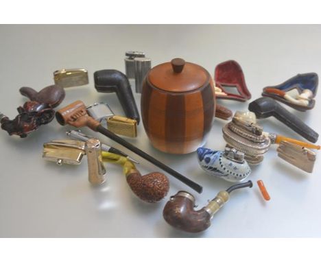 A collection of pipesmoking related items including a tobacco jar, a collection of treen carved pipes, pipe cases, lighters, 