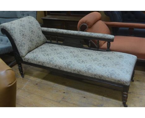 An Edwardian walnut chaise longue with scroll end and baluster support backrest, upholstered in tapestry machine woven fabric