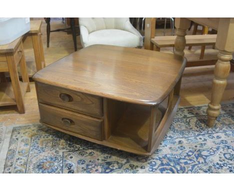 An Ercol elm coffee table, the shaped squared top with rounded angles and open sides, fitted two side drawers, with turned re