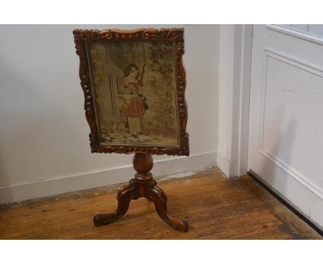 A Victorian rosewood snap top firescreen with relief carved border and glazed Berlin woolwork panel depicting a Young Girl wi