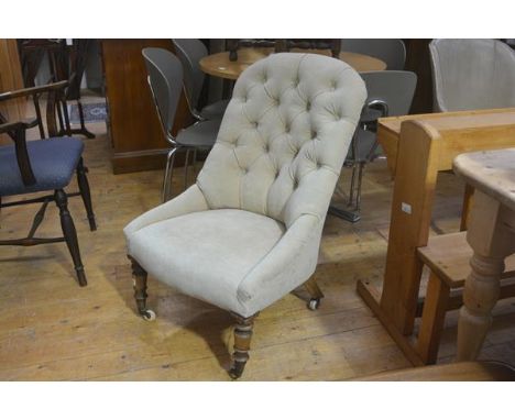 A Victorian nursing chair with upholstered button back and side supports and seat, in fawn plush, raised on turned tapered su