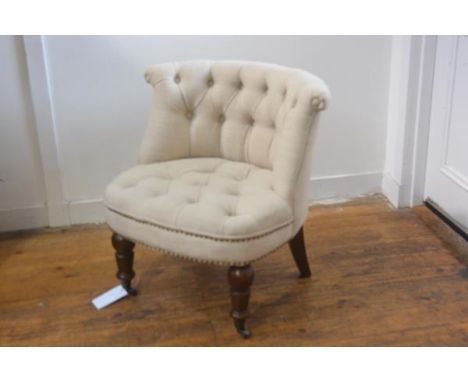 An early 19thc style low chair with button back, in cream linen, with studded detail, on turned tapered supports, with metal 