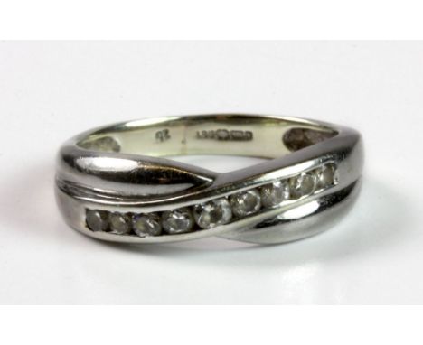 A 9ct white gold stone set crossover ring, (K).