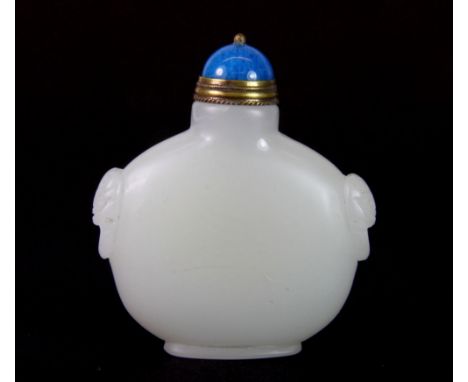 A Chinese carved pale celadon jade snuff bottle decorated with lion ring handles and a gilt and blue hardstone stopper, H. 6.