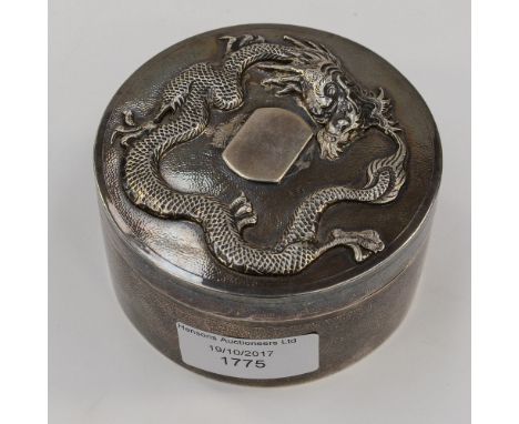 A white metal and gilt lined trinket box and cover, the cover being embellished with a raised three toe dragon, stamps to the