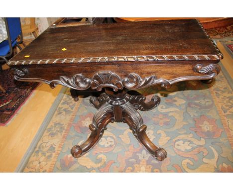 A 19th Century oak pedestal card table, raised on a turned column, standing on four scroll carved legs