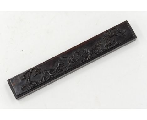 A Chinese carved hardwood block, decorated with dogs either side of a pearl within a prunus ground