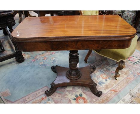 An early Victorian mahogany fold over card table, raised on a turned column and standing on a platform base