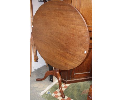 A George III mahogany tilt top tripod table, the top made from a single plank, raised on a turned column and standing on cabr