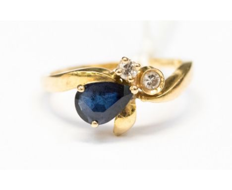 An eighteen carat gold and sapphire ring, having a pear shape sapphire with two diamonds set in a foliate design, approx ring