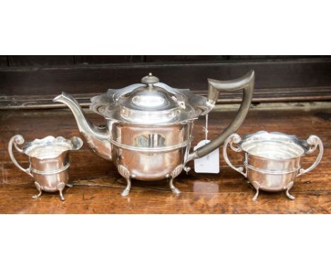 A three piece silver tea set comprising teapot with ebony handle and finial, twin handled sugar and milk, Birmingham 1908 and