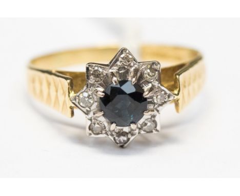 A sapphire and diamond 18ct yellow gold star design cluster ring, the round mixed cut sapphire measuring approximately 5mm by