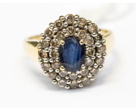 A sapphire and diamond cluster 18ct yellow gold ring,m the centre oval cut sapphire measuring approx 7 by 5 mm with diamond t