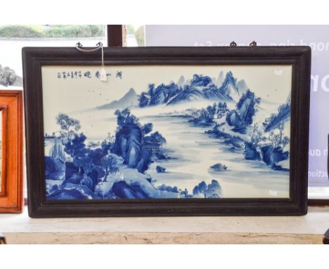 A framed Chinese ceramic plaque, handpainted in blue and white with mountains and lake scene, measuring approx 42cm x 76cm