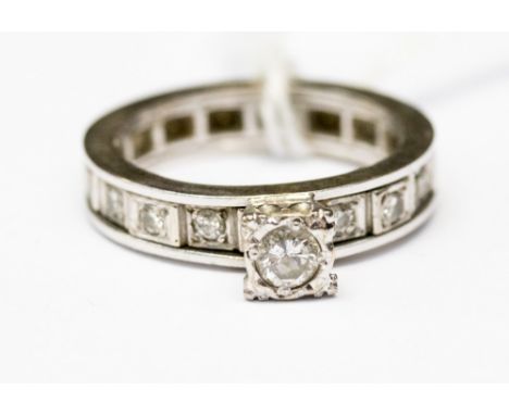 A diamond white metal solitaire eternity ring, the centre raised diamond weighing approximately 0.25 carat, with small diamon