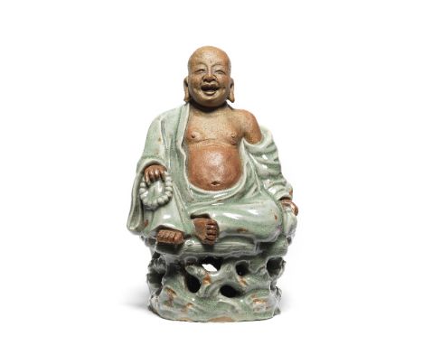 A RARE LONGQUAN CELADON-GLAZED FIGURE OF BUDAIMing DynastyThe Laughing God heavily potted seated on a deeply-pierced rockwork