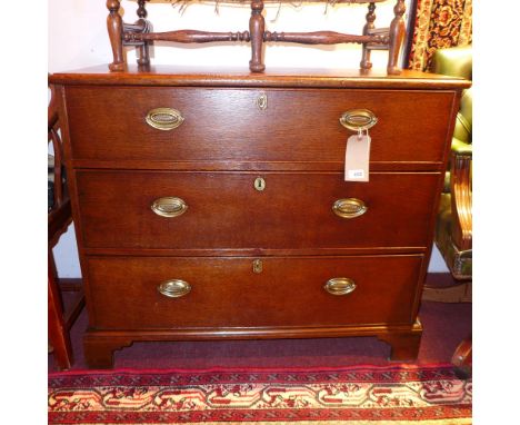 A Georgian oak chest fitted three long drawers with brass oval plate handles on bracket feet