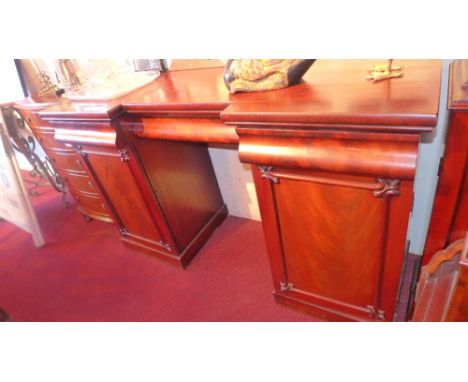 A Victorian flame mahogany inverted breakfront pedestal sideboard having three short cushion drawers above two cupboard doors