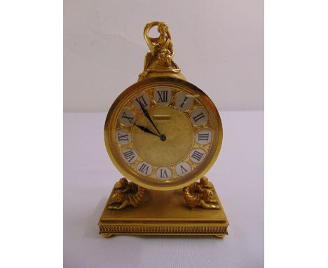 A French Luxor gilt mantle clock of circular form surmounted by a classical figurine, the rectangular base on four bun feet