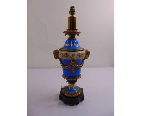 A French Sevres style lamp base with gilt rams heads, decorated with putti and gilded metal mounts