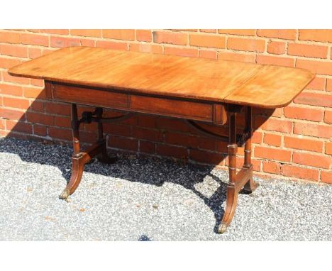 An early 19th century mahogany sofa table, with drop end sections, fitted two frieze drawers the trestle ends being twin ring