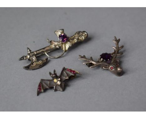 An Amethyst and Garnet Stag Head Silver Brooch, Scottish Axe and Thistle White Metal Brooch and a Small Jewellers Bat Brooch 