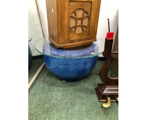 A CHINESE ROUNDED CYLINDRICAL BLUE GLAZED PLANTER WITH A CLEAR GLASS CIRCULAR COFFEE TABLE TOP.   Dia. 72cms.
