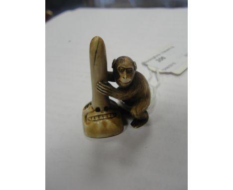 A Meiji period ivory netsuke of a monkey holding a mask
