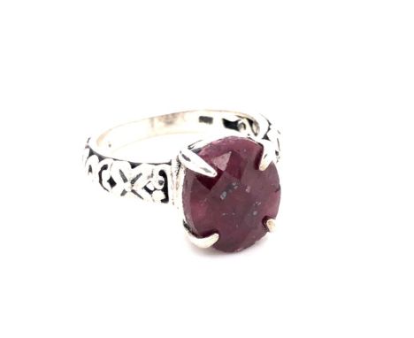 A RED CORUNDUM CARVED RING. THE OVAL FACET CUT RUBY IN A FOUR CLAW SETTING, WITH CARVED OPEN SHOULDERS. UNHALLMARKED AND STAM