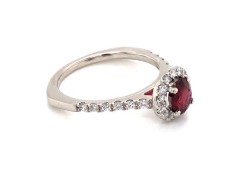 A 950 PLATINUM HALLMARKED ALMANDINE GARNET AND DIAMOND HALO RING. THE GARNET APPROX 6 x 5mm, SURROUNDED BY A HALO OF DIAMONDS