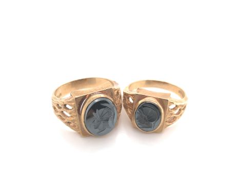 A PAIR OF HIS AND HERS HEMATITE INTAGLIO TROJAN HEAD CARVED RINGS. STAMPED 9ct , FOR SGW, AND ASSESSED AS 9ct YELLOW GOLD. FI