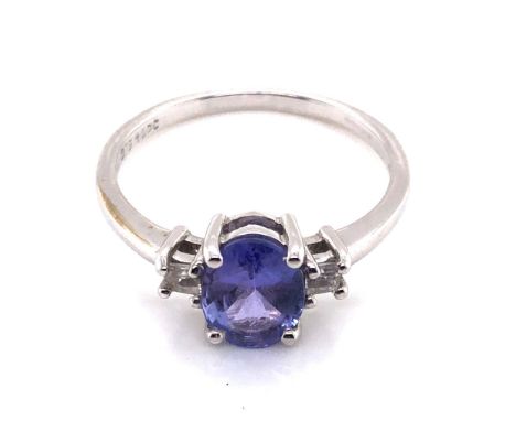 A TANZANITE AND CUBIC ZIRCONIA HALLMARKED 9ct WHITE GOLD DRESS RING. THE OVAL TANZANITE IN A FOUR CLAW SETTING FLANKED BY PRI