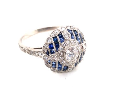 AN EDWARDIAN STYLE DARK CORNFLOWER BLUE SAPPHIRE AND OLD CUT DIAMOND DOMED CLUSTER RING. THE CENTRAL DIAMOND IN A BEZEL SETTI