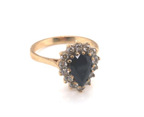 A 9ct HALLMARKED GOLD DARK BLUE SAPPHIRE PEAR CUT CLUSTER RING. THE SAPPHIRE SURROUNDED BY A CLUSTER OF WHITE CLAW SET CUBIC 