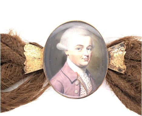 A LATE GEORGIAN PORTRAIT MINIATURE AND WOVEN HAIR BRACELET IN A 14ct YELLOW GOLD FRAME WITH ARTICULATED MOUNTS. THE HAND PAIN