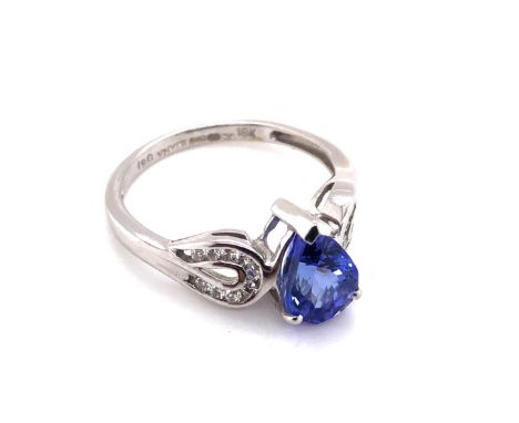 AN 18ct WHITE GOLD HALLMARKED TANZANITE AND DIAMOND RING. THE PEAR CUT TANZANITE IN A RAISED THREE CLAW SETTING WITH FANCY DI