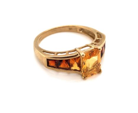 A 9ct YELLOW GOLD HALLMARKED OMBRE CITRINE DRESS RING. THE CENTRAL CITRINE IN A RAISED FOUR CLAW SETTING WITH DARKER SHADES O
