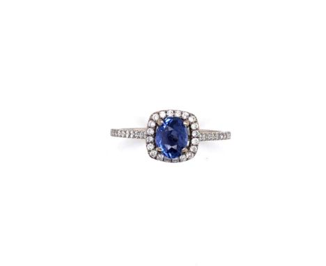 A SAPPHIRE AND DIAMOND RING HALO RING. THE CENTRAL SAPPHIRE IN A RAISED FOUR CLAW SETTING,  APPROX MEASUREMENT  6.5 x 5mm, SU