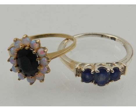 A 9 carat yellow gold, sapphire, and opal cluster ring, together with a 9 carat yellow gold and blue sapphire three stone rin