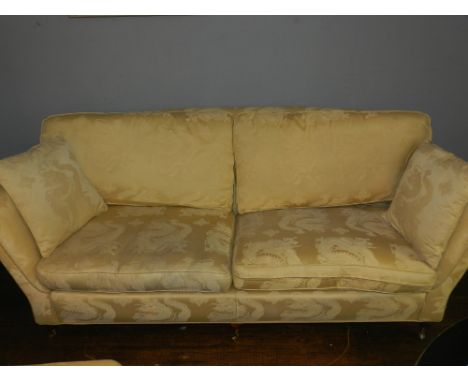 A modern three seater sofa and matching armchair upholstered in gold dragon pattern fabric