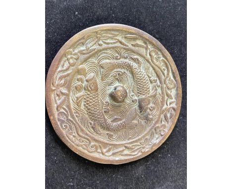 A antique bronze Chinese hand mirror with fish decoration