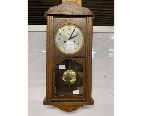 A vintage wooden case wall clock with key and pendulum, shipping unavailable
